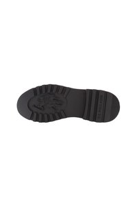 Suela de zapato de goma negra con una superficie texturizada, que presenta un emblema de logo y patrones de piso pronunciados para agarre y durabilidad.