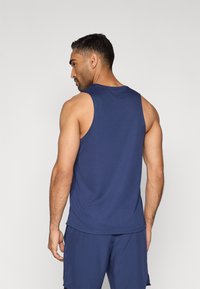 Dunkelblaues Tanktop mit rundem Halsausschnitt und Armausschnitten, gefertigt aus einem glatten Stoff. Verfügt über eine lockere Passform und ein Detail an der Rückseite der Schulter.