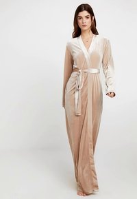 Lunga vestaglia in velluto beige con maniche lunghe, design avvolgente e cintura abbinata. Dettagli in raso lungo il davanti e il colletto.