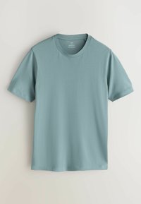 Zila muskuļu silueta T-krekls no mīksta kokvilnas. Tam ir klasisks apaļš kakla izgriezums un īsas piedurknes ar gludu, vienmērīgu tekstūru.