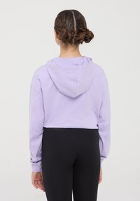 Felpa corta viola con cappuccio sul retro, maniche lunghe e polsini a costine, abbinata a leggings neri. Tessuto morbido con una superficie liscia.