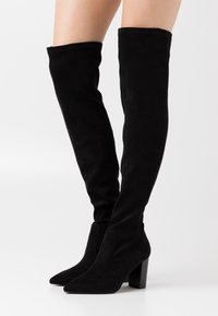 Botas negras de ante hasta la rodilla, con punta afilada y tacón cuadrado, de textura suave y sin hardware o detalles visibles.