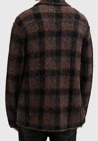 Brun och svart rutig ullskjortjacka med en mjuk, texturerad finish och krage, med en avslappnad passform och något nedsänkt nederkant.