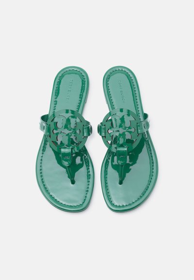 Πράσινα σανδάλια από συνθετικό δέρμα με πατέντα, με διακοσμητικό σε σχήμα κυκλικού λογότυπου και υφή στην επιφάνεια του πέλματος, ενώ η πάνω επιφάνεια είναι ομαλή.