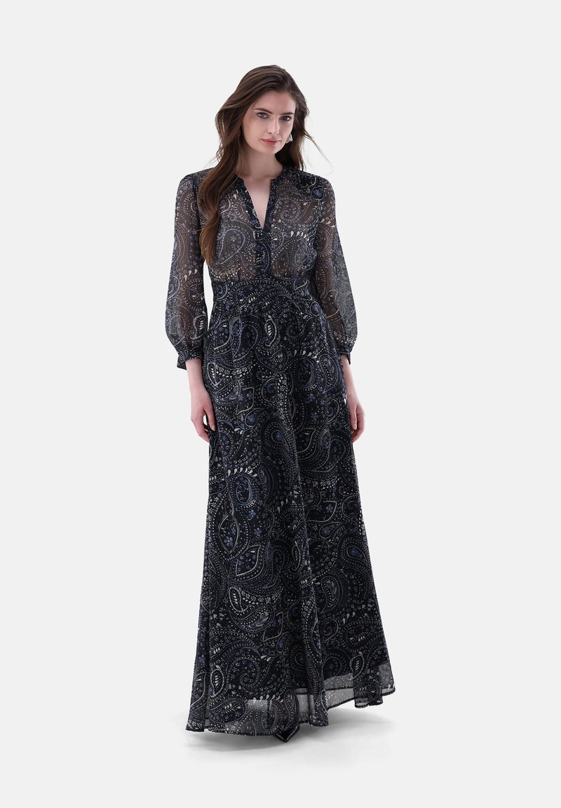 Abito lungo in tessuto trasparente di colore blu navy, con un motivo paisley, con bottoni sulla parte anteriore e maniche lunghe a palloncino. Design fluido con vita aderente.