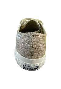 Złote, błyszczące sneakersy z tkaninowym wierzchem, wyściełanym wnętrzem, białą gumową podeszwą i fakturowanymi detalami na palcach i pięcie.