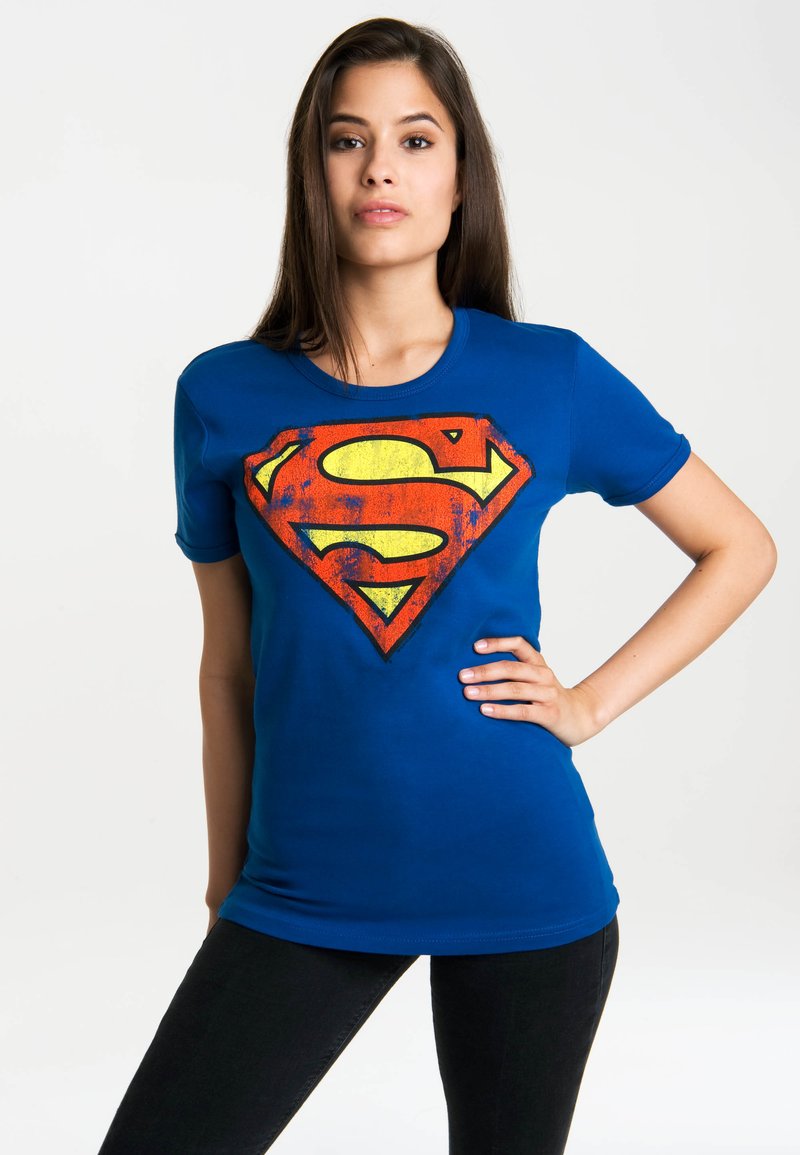 Blue cotton t-shirt featuring a large red and yellow Superman logo. Short sleeves, crew neck design, and fitted silhouette.