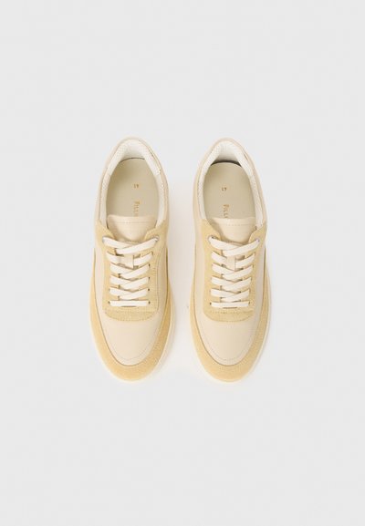 Beige nahk- ja sametist lace-up spordijalatsid, millel on sujuv disain, heledad aktsendid ja tekstureeritud varbakatte osa.
