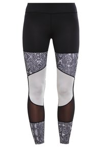 Leggings neri con pannelli in stampa serpente in tonalità di grigio, sezioni bianche e inserti in rete nera vicino alle ginocchia. Texture liscia su tutta la superficie.