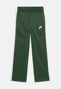 Zaļi Nike treniņu bikses ar baltām sānu svītrām, elastīgu jostu un mazu baltu logo uz kreisā ceļa. Gluda auduma tekstūra.