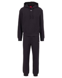 Svart sweatshirt och sweatpants set. Luvtröja med vit logotyp, ribbade ärmar. Byxorna har resårmidja och avsmalnande ben. Mjukt tyg.