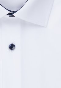 Camicia bianca con colletto classico, bottone scuro e dettagli blu navy lungo il bordo del colletto. Tessuto morbido, design strutturato.