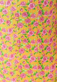 Blommönstrad tyg med rosa rosor och gröna blad på en gul bakgrund, med en strukturerad, ribbad yta.