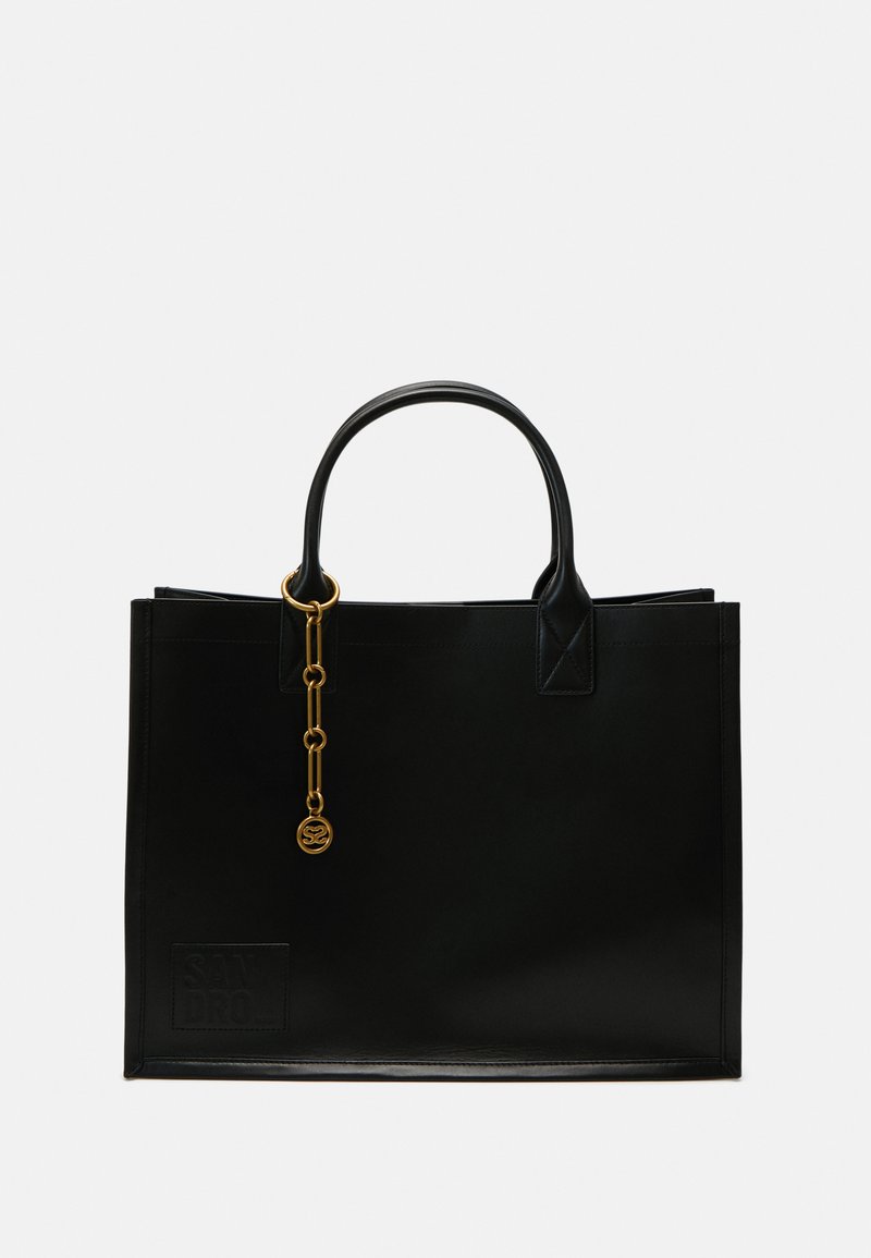 Sac tote en cuir noir avec une texture lisse, une forme structurée, deux poignées supérieures et un détail en chaîne dorée avec logo.