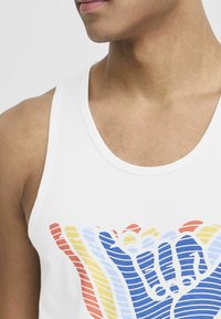White tank top featuring a colorful graphic design of hands in shades of red, yellow, and blue with horizontal striping.