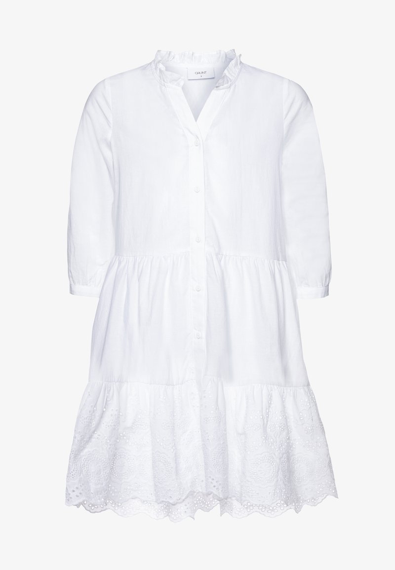 Robe en coton blanc avec fermeture à boutons, col à volants et manches trois-quarts. Caractérisée par un ourlet à volants avec des accents brodés.
