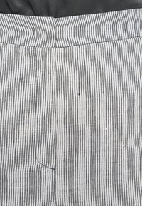Striped fabric trousers featuring vertical navy and white stripes, with a smooth texture and a back pocket detail at the waistband.