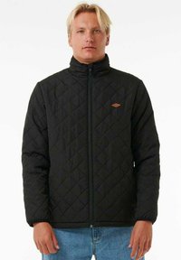 Black quilted jacket with a high collar, featuring a front zipper and a small brown logo detail on the chest. Texture is smooth.