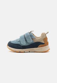 Blå och marinblå mockasneakers med beige detaljer. Har två kardborrestängningar, perforerad tå och en texturerad gummisula.