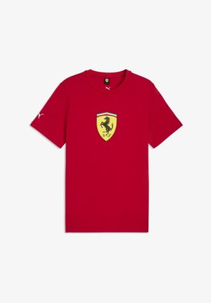 T-shirt rossa a maniche corte con logo scudetto Ferrari giallo che presenta un cavallo nero rampante al centro davanti e logo Puma bianco sulla manica destra e sul colletto.