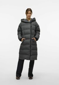 Langer, puderartiger Mantel in Dunkelgrau mit Kapuze, Reißverschluss und seitlichen Taschen. Verfügt über ein gestepptes Design zur Isolierung und Wärme.