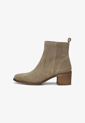 Bottine en daim beige avec un talon bloc en bois de 5 cm, bout arrondi, fermeture éclair latérale et languette à l'arrière.