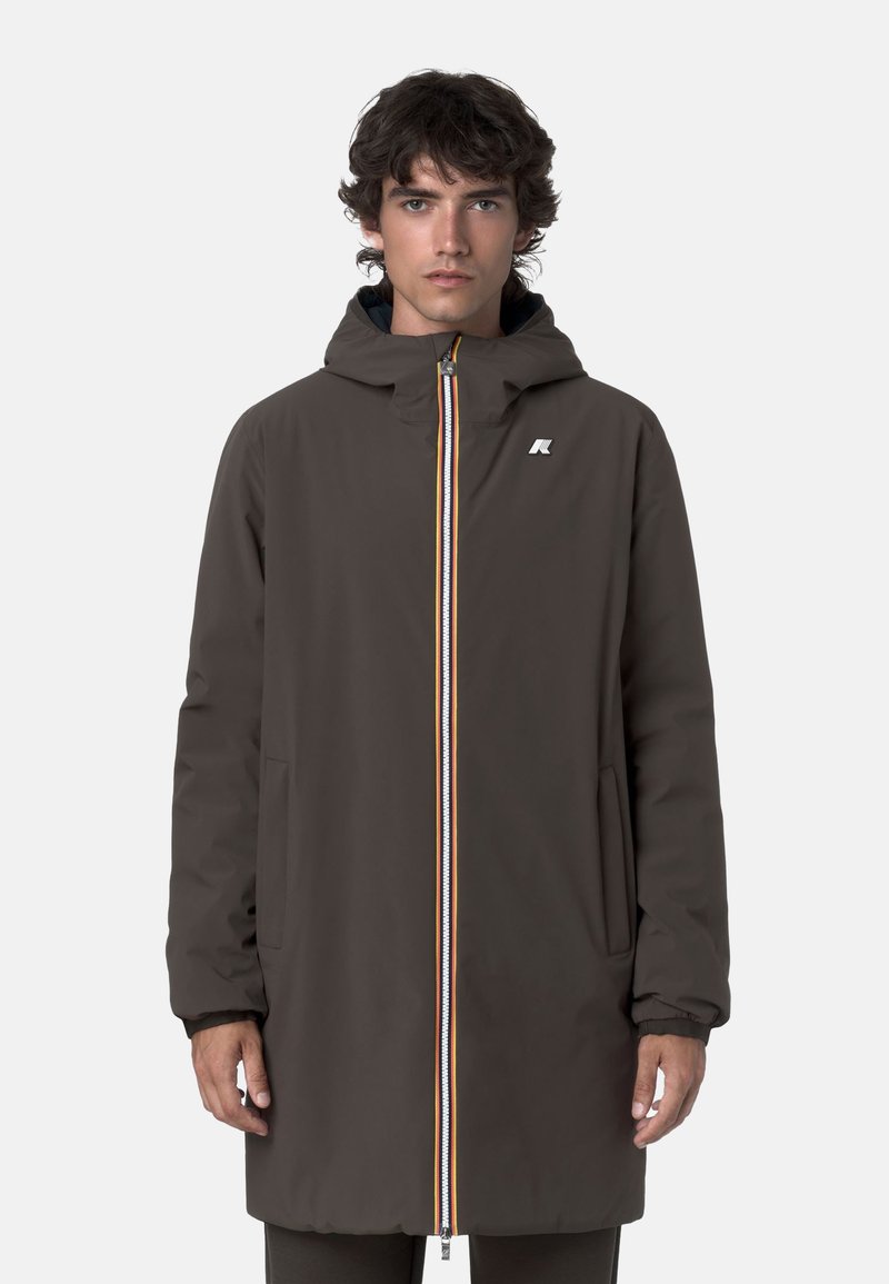 Cappotto esterno marrone con cappuccio, chiusura frontale con zip caratterizzata da strisce colorate e tasche laterali, realizzato in materiale liscio e resistente all'acqua.