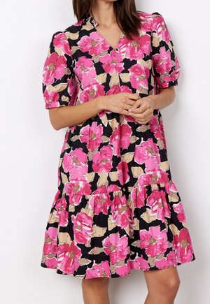 Svart klänning med stora rosa blommor, korta puffärmar och en lager-på-lager kjol. Tillverkad av lättviktsmaterial, med V-ringning.