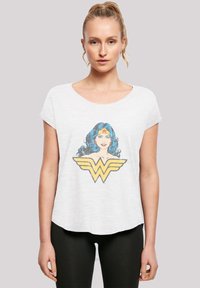 Hvit t-skjorte med kort erme som har et fargerikt Wonder Woman-motiv med blått hår og gule detaljer, kombinert med sorte leggings.