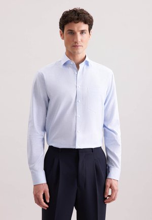 Lichtblauwe shirt met lange mouwen in een textuurstof, met een button-down kraag, één borstzak en witte knopen. Gecombineerd met donkere broeken.