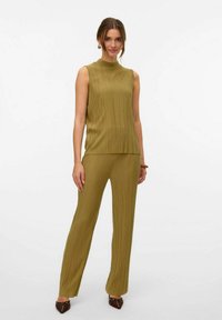 Olijfgroene geplooide mouwloze top en bijpassende broek. Glad textuur, ontspannen pasvorm. Bruine puntige schoenen maken de outfit compleet.