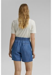 Denim-shortsit, joissa on joustava vyötärö, kaksi takataskua ja rento istuvuus, yhdistettynä vaaleanharmaaseen lyhythihaiseen paitaan.