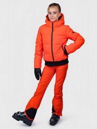 Oranžová nadýchaná bunda s kapucí a černými detaily, doplněná oranžovými lyžařskými kalhotami s černým lemem, nošená s lyžařskými botami a rukavicemi.