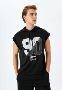 Zwarte mouwloze hoodie met een groot wit nummer "90" en de tekst "RUN FIND Yourself" in een contrasterend lettertype. Gladde stof met een capuchon.