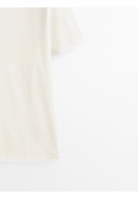 T-shirt beige clair à manches courtes en coton, avec une coupe décontractée et une texture lisse, un col rond et sans embellissements.