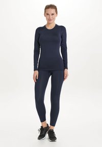 Navy pitkähihaisessa urheilupaidassa ja tiukoissa leggingseissä, jotka on valmistettu joustavasta kankaasta, sileästä tekstuurista, ja joissa on sovitettu muotoilu ilman näkyviä logoja.