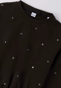 Zwarte sweatshirt met een ronde halslijn, voorzien van verspreide zilveren studs in verschillende vormen, waaronder vierkanten en cirkels, voor extra textuur.