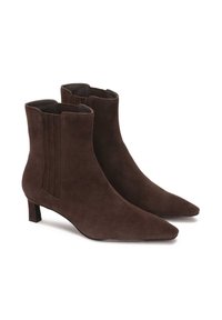 Botas de tobillo de ante marrón con punta afilada, tacón bajo en bloque y detalles elásticos laterales para un uso cómodo. Suela plana, costuras mínimas.