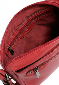 Borsa in pelle rossa con una texture liscia, dotata di una tasca interna con zip e foderata. L'esterno ha una chiusura con zip e un'etichetta metallica.