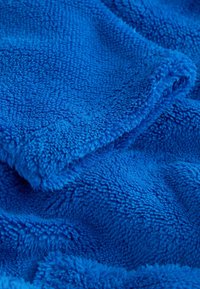 Mäkká, textúrovaná modrá fleece látka s hustými, nadýchanými vláknami a jemnými záhybmi, ktoré vytvárajú útulný, teplý vzhľad.