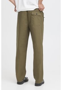 Løse bukser i olivengrøn lavet af blødt stof. Har en enkelt baglomme med knap og lige, afslappede ben.