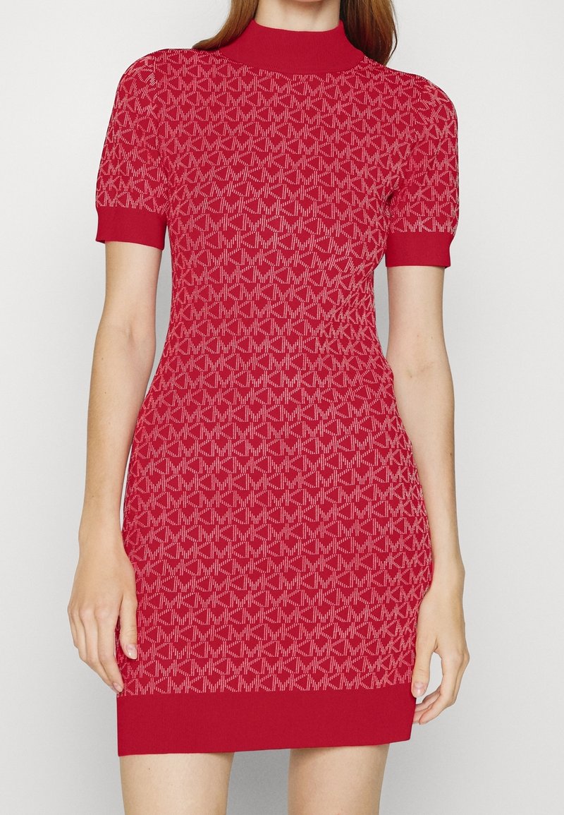 Femme portant une robe ajustée en maille rouge à manches courtes avec un motif répétitif "MK" en rouge plus clair.