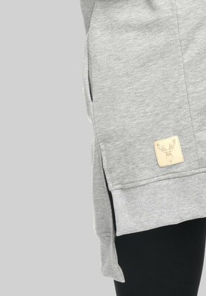 Grauer Sweatshirt mit geripptem Saum, seitlichem Schlitz und einem Etikett mit Hirschdesign. Hergestellt aus weichem, strukturiertem Baumwoll-Mischgewebe.