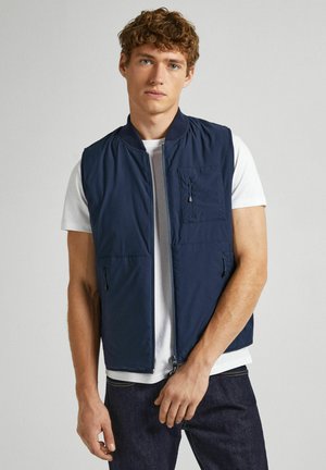 Gilet senza maniche blu navy realizzato in tessuto liscio, dotato di una zip frontale, tasca sul petto con zip e due tasche laterali.