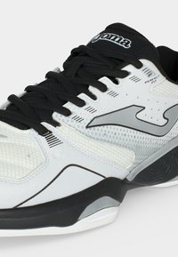 Λευκό και μαύρο αθλητικό παπούτσι με μαύρα κορδόνια, πλέγμα υφάσματος και λογότυπο «Joma» στο πλάι και στη γλώσσα, με κείμενο «Perfect Fit».