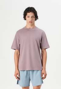 Short-sleeve, crew-neck t-shirt in soft lavender fabric; relaxed fit; paired with light blue shorts featuring dark blue side accents.