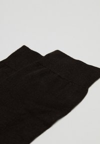 Sort, struktureret strømpebukser med en glat, elastisk topstrop, der har et fint strikket design og ensartet farve hele vejen igennem.