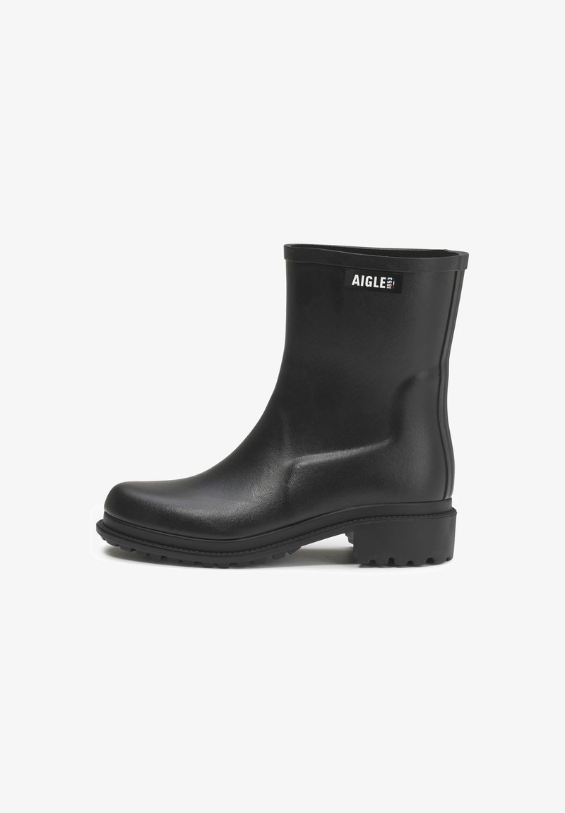 Bottes en caoutchouc noires jusqu'à la cheville avec une texture lisse, un embout arrondi et une semelle striée. Elles présentent une étiquette logo sur le côté extérieur.