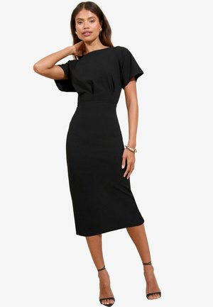 Abito midi nero con maniche corte e ampie e vita aderente. Tessuto liscio con una leggera lucentezza. Abbinato a décolleté nere con cinturino alla caviglia.