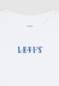 White cotton T-shirt featuring a blue embroidered "LEVI'S" logo with stylized text and numbers, round neckline, smooth texture.